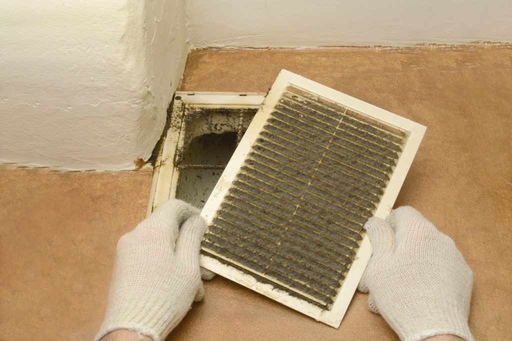 Man removes dust ventilation grilles in white gloves