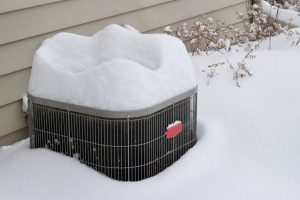View of an exterior air conditioner unit covered with deep snow following a snow storm