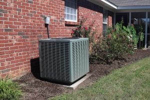 Air Conditioner system next to a home, modern clean with bushes and brick wall
